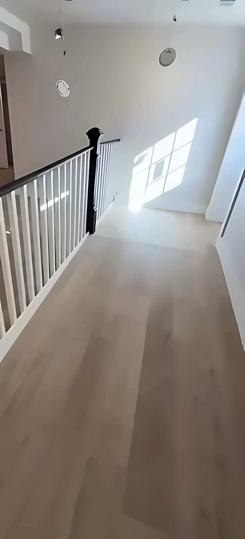 Sunlit landing with new flooring and a black railing